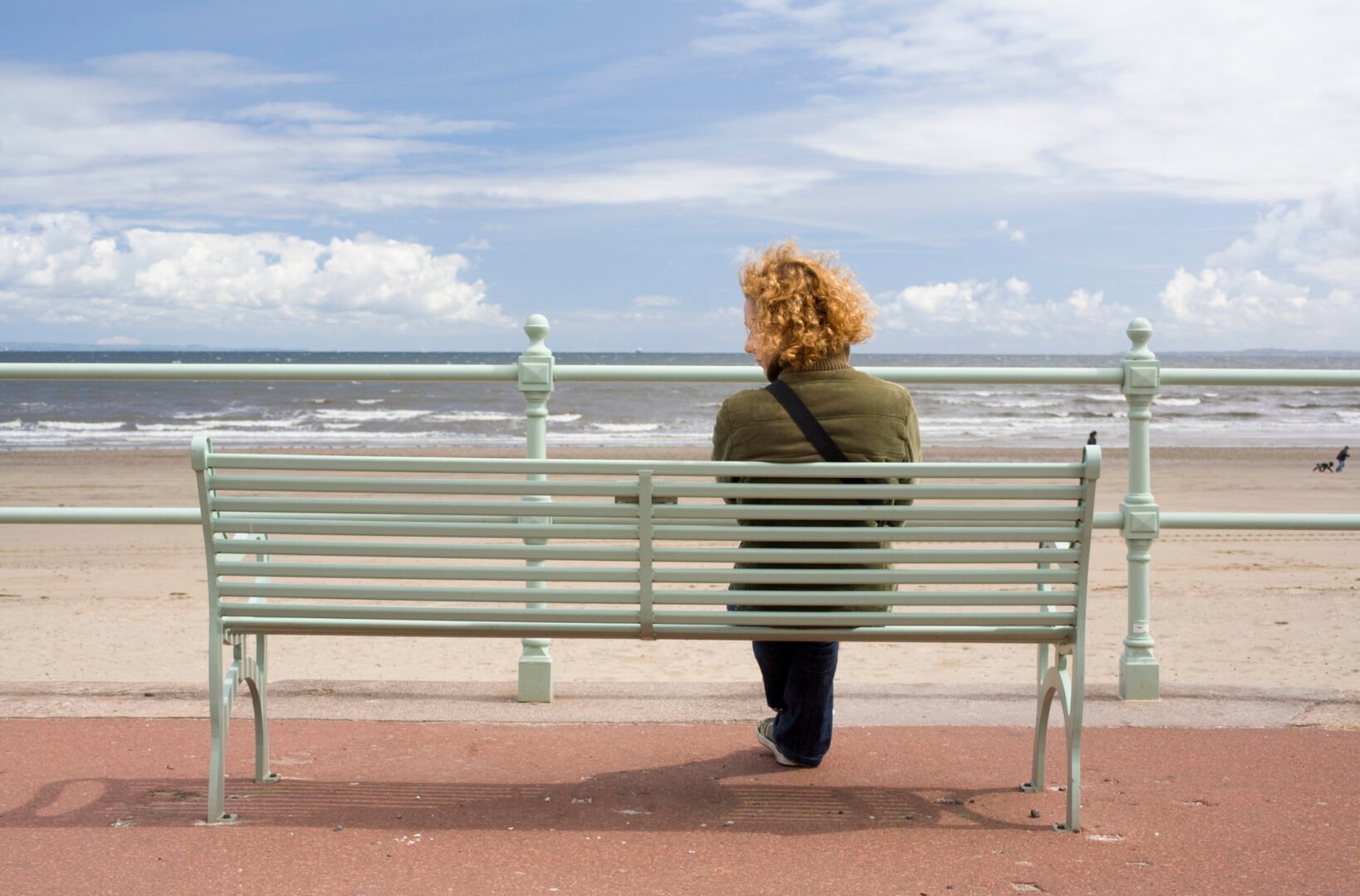 Young woman looking at something along the sea front, at Portobello, Edinburgh, Scotland.