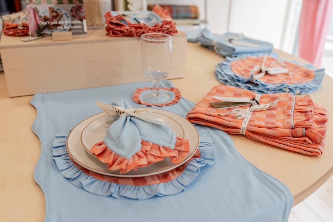 dinner set up featuring a bright blue table runner and bright apricot checkered napkins and placemats.