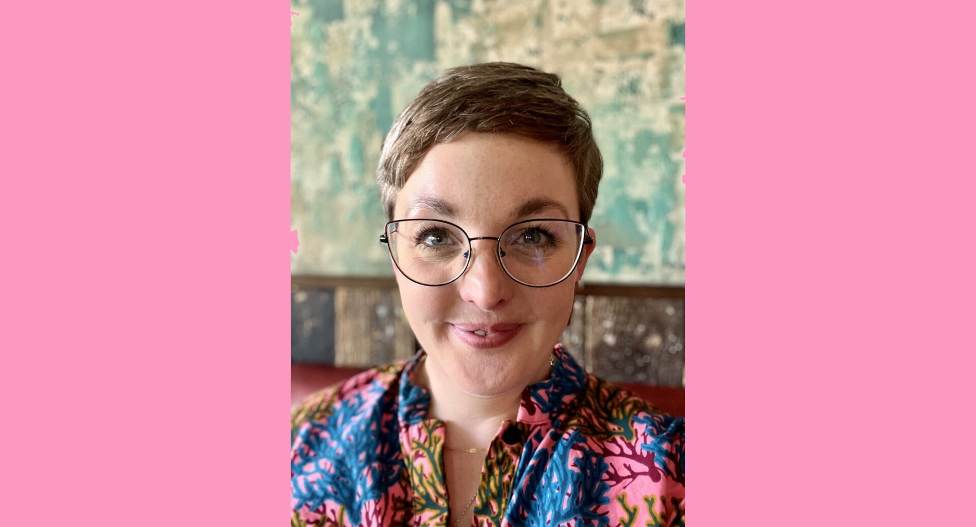 A head and shoulders portrait shot of Dr Lizzie Swarbrick. She has short brown hair, round framed metal glasses and a multicoloured abstract top.