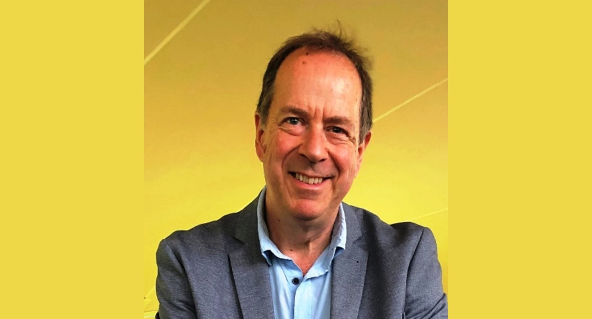 A head and shoulders shot of speaker Andy Mitchell in a suit jacket and open-necked shirt