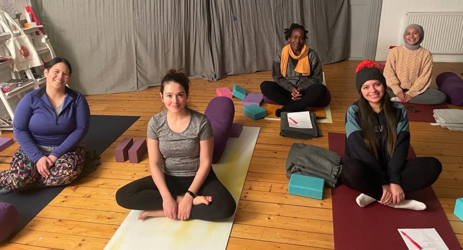 Five women sitting on exercise mats on the floor