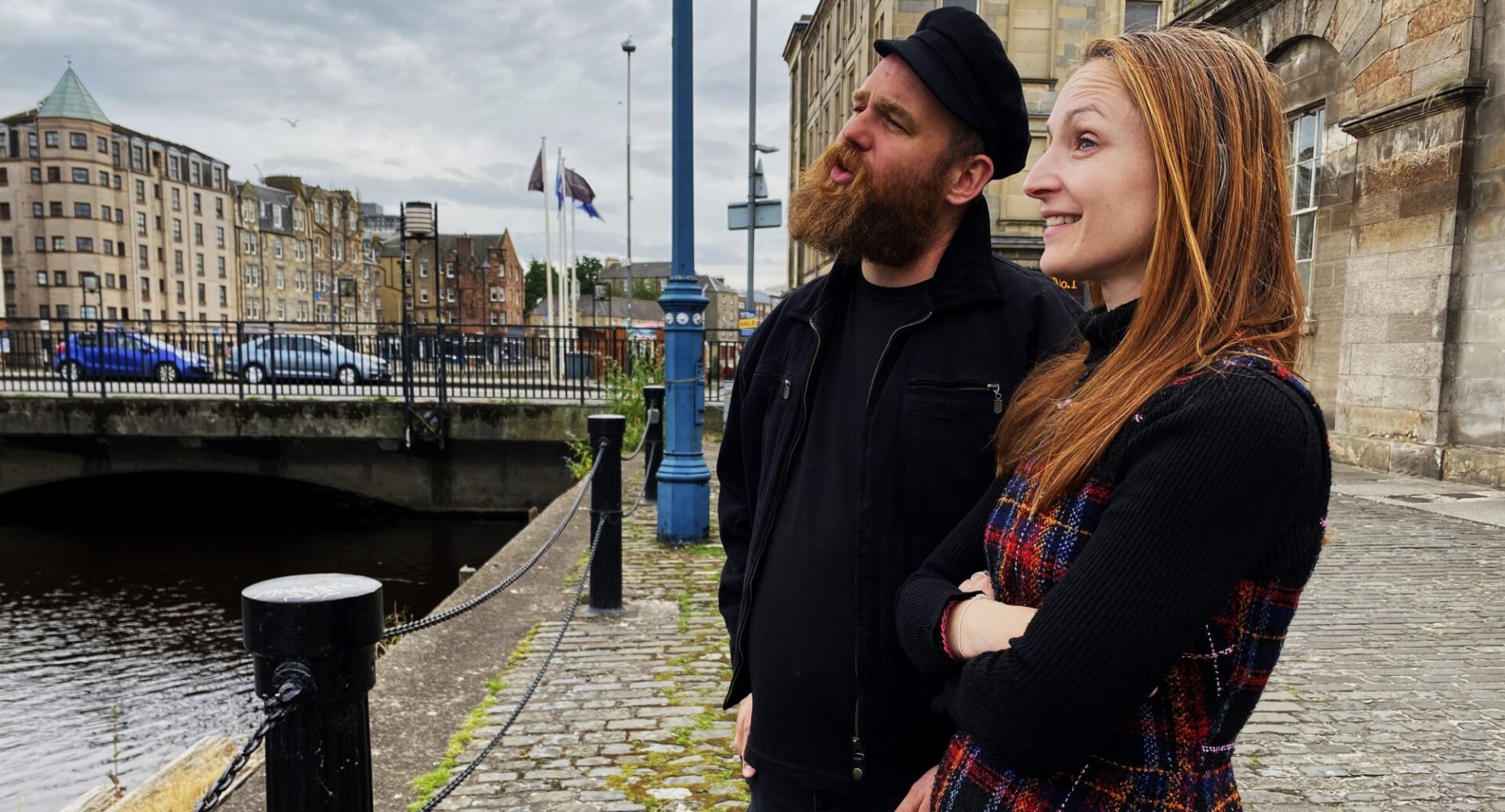 Actors Gregor Davidson and Mairi Jayne Weir beside Leith Custom House looking out at the Water of Leith from the wharf.