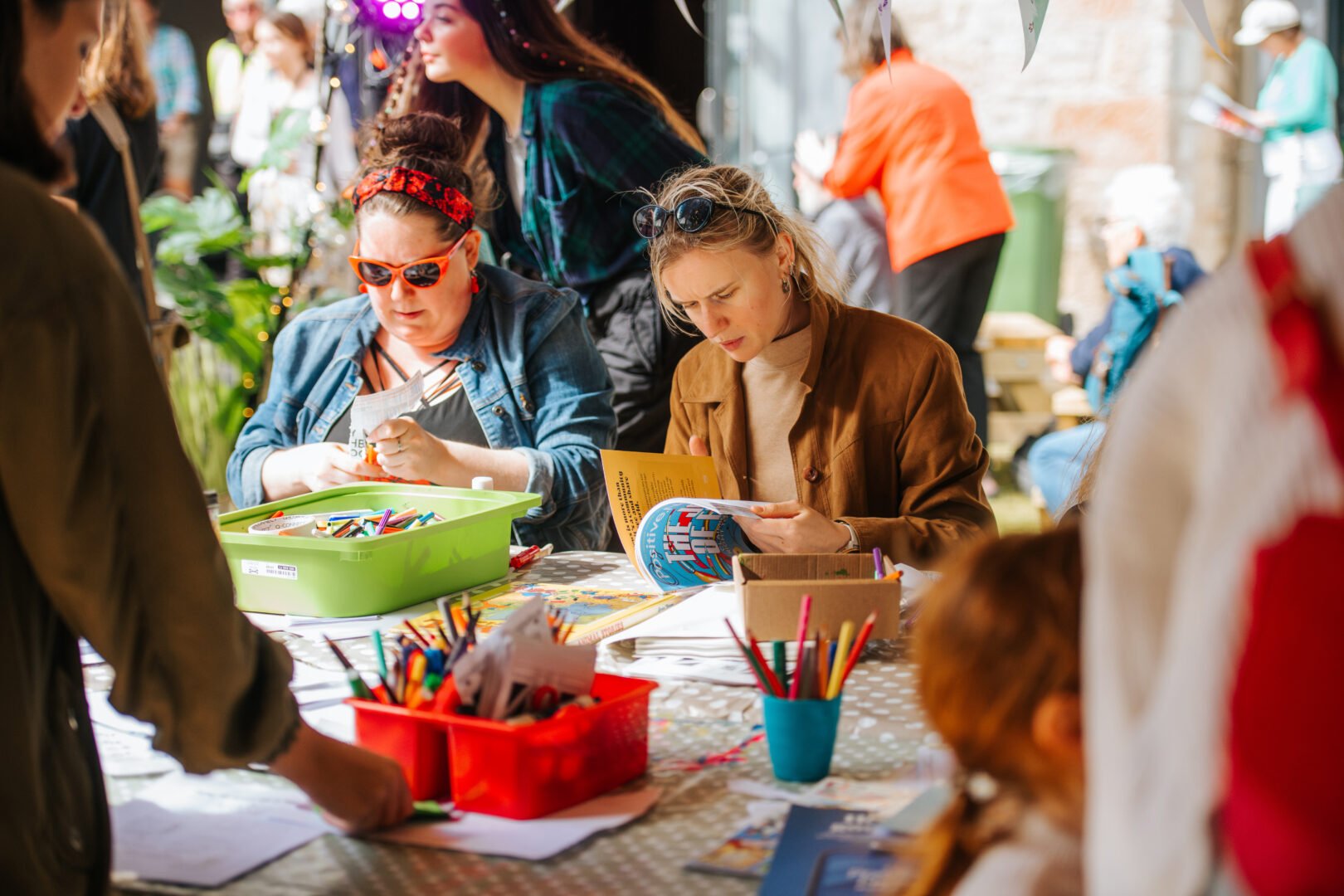 Two woman sitting down making crafts
