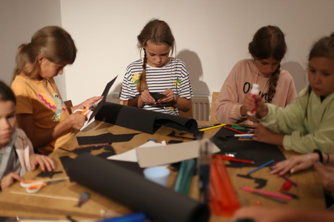 Kids cutting out images on black paper for Summer Camp Manual Cinema