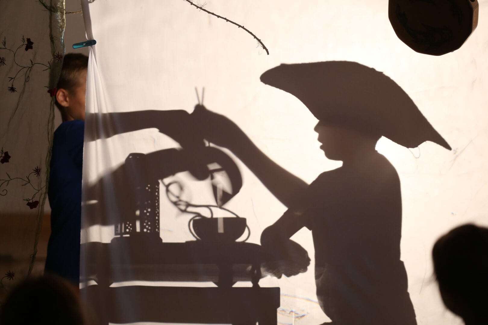 Kids creating shadow images behind a white sheet for the Summer Camp Manual Cinema