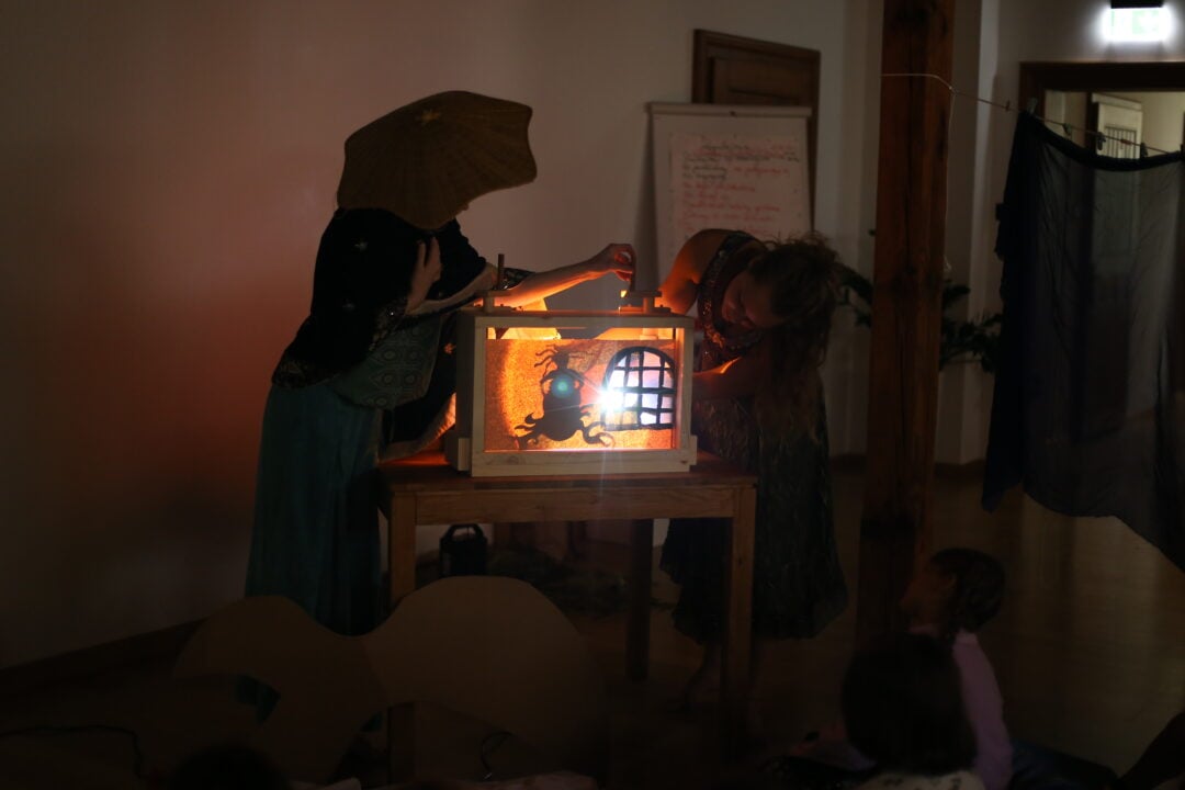 Adults using a light box to create shadow images at Summer Camp Manual Cinema