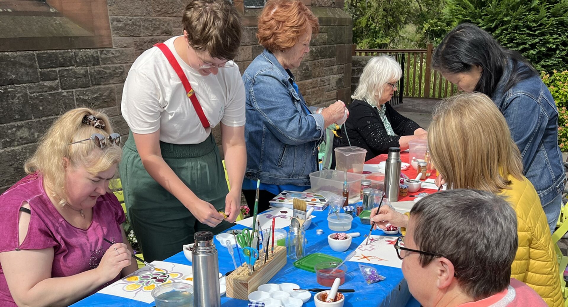 A group of women sitting around a table on which arts and crafts supplies are laid out