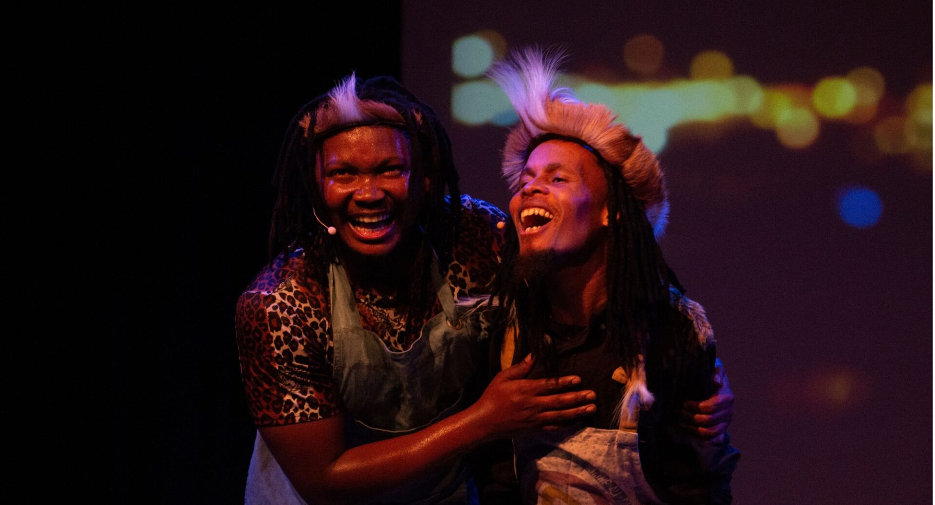 Two people laughing against a backdrop of bokeh lighting