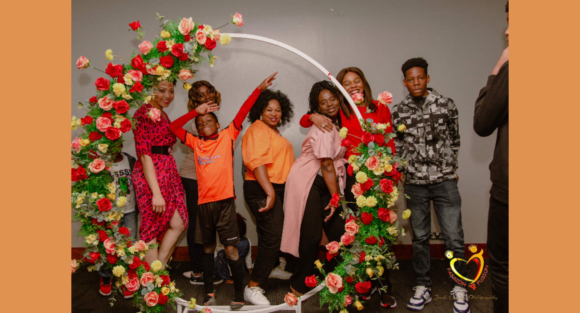 A group of smiling people standing behind a large circular garland of roses