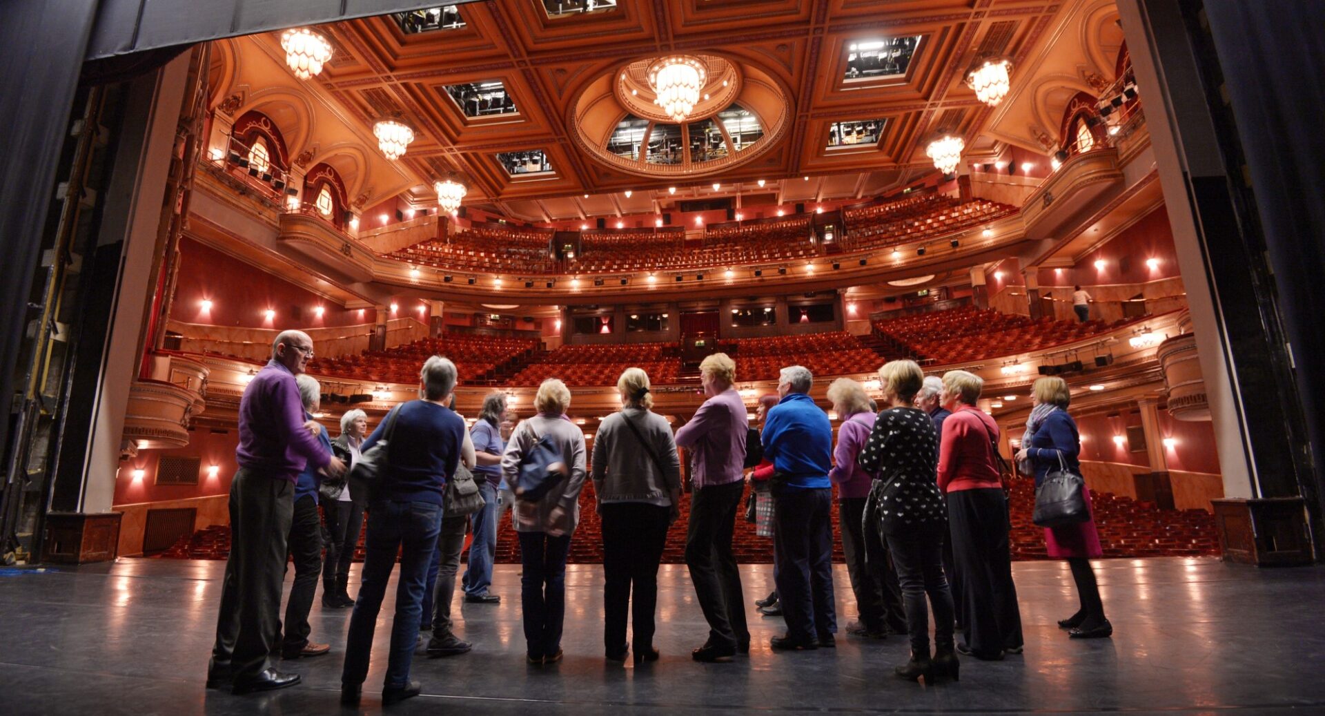 A group of participants attending the backstage tour. The lit up auditorium can be seen in the background