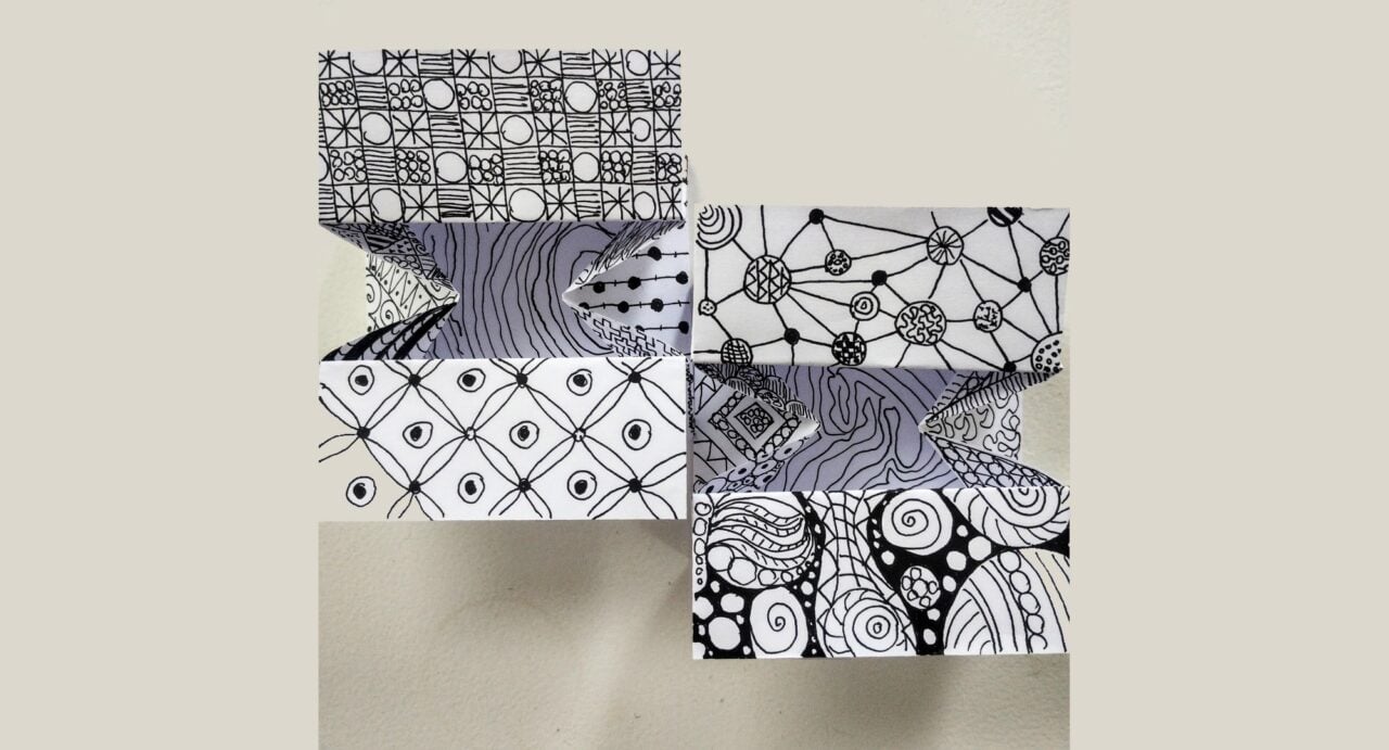 White folded paper with black ink abstract designs on it