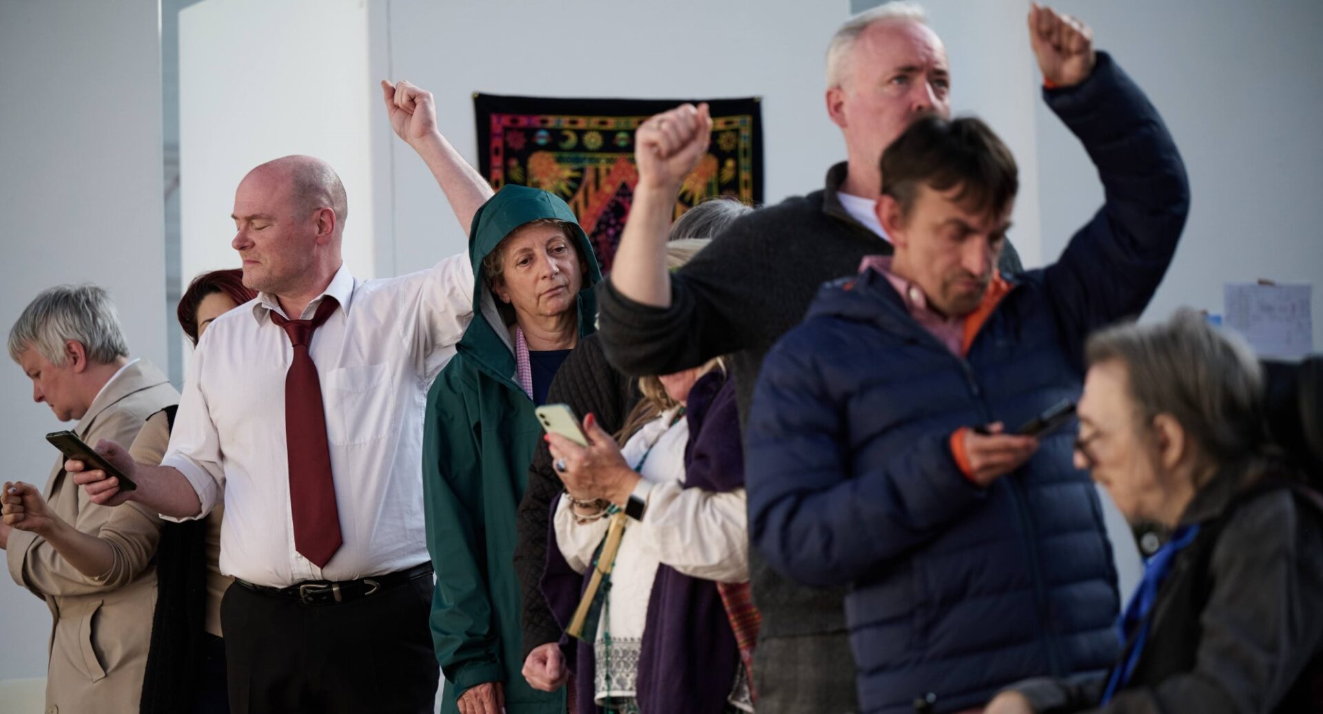 Actors during the Made to Connect show standing in line, some with arms aloft as if holding on in a bus