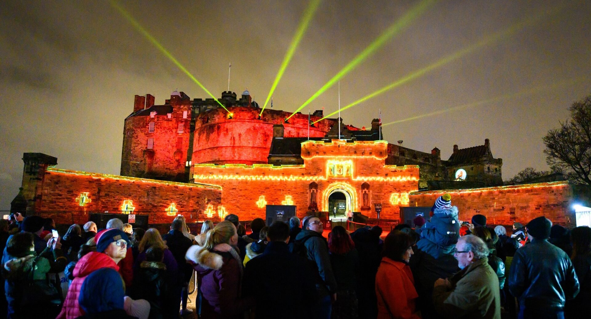 Edinburgh Castle lit up with crowds in the foreground