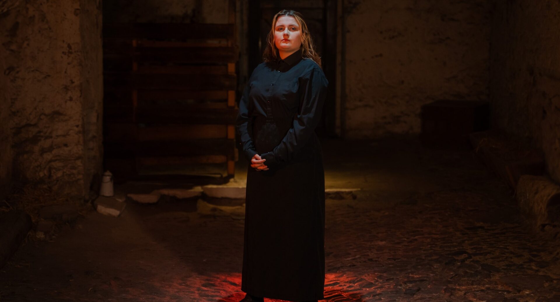 A young female tour guide dressed in black, standing in Mary King's Close