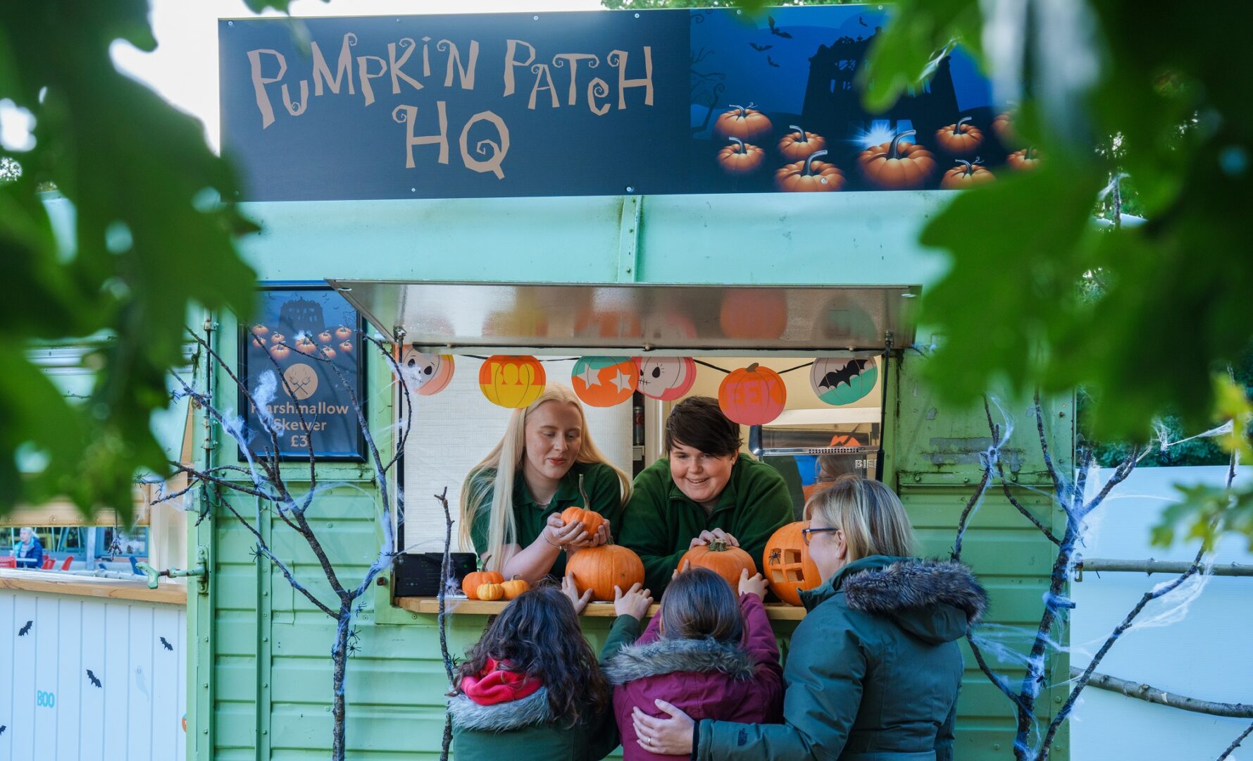 A family at the booth of the Pumpkin Patch at Dalkeith Country park talking to members of staff.