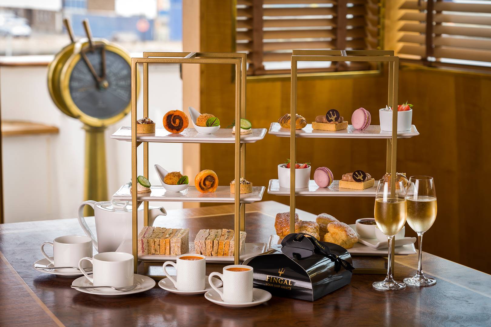 Sweet and savoury Afternoon Tea stands with glasses of Champagne, teacups and amuse bouches.