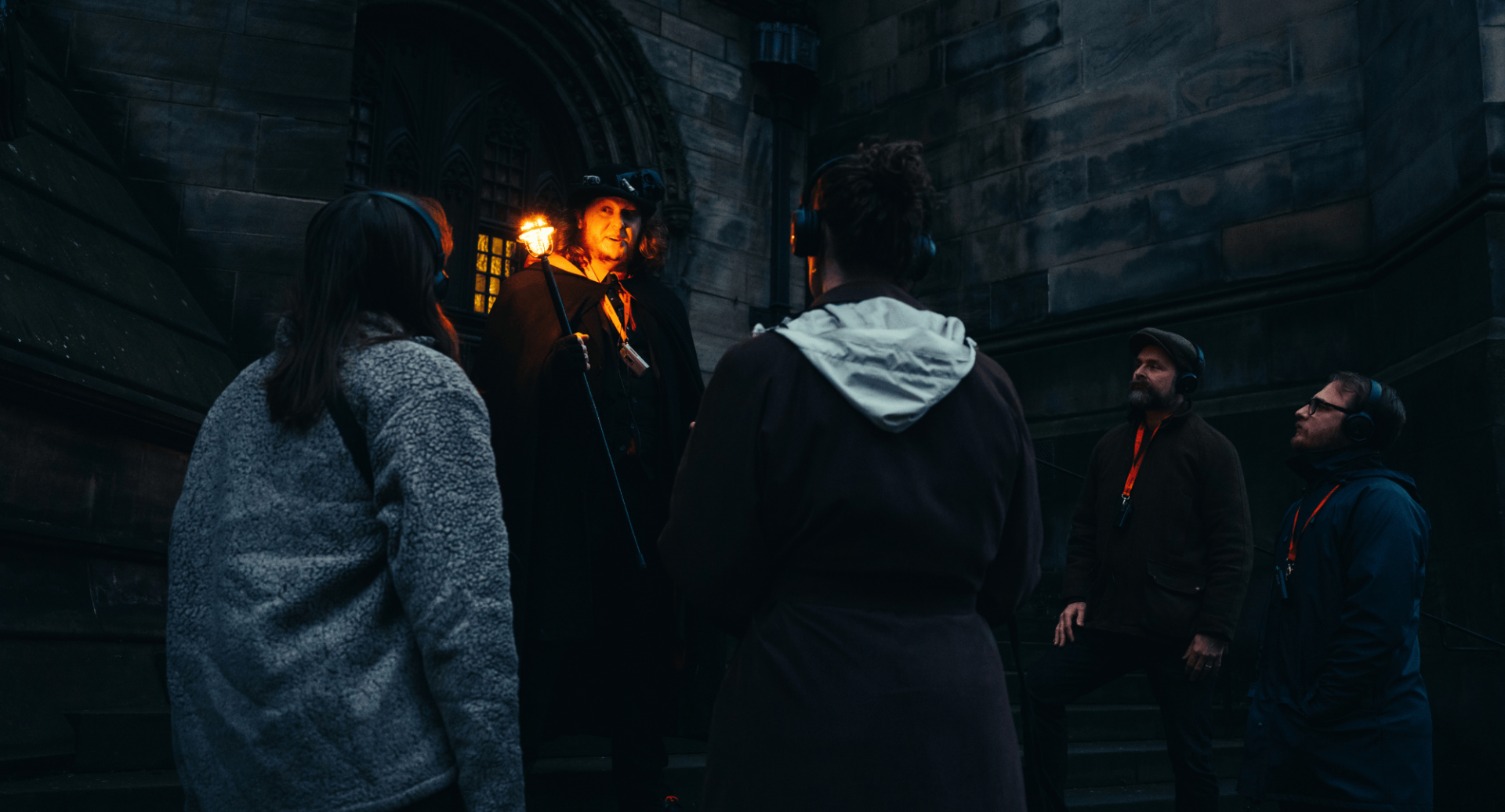 Tour guide holding a torch with a tour group outside Mercat Tours