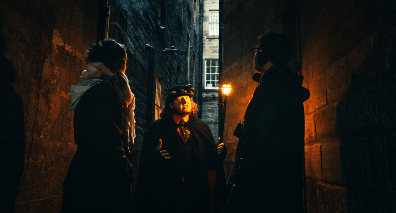 Tour Guide leading tour in a close of Edinburgh royal mile at night