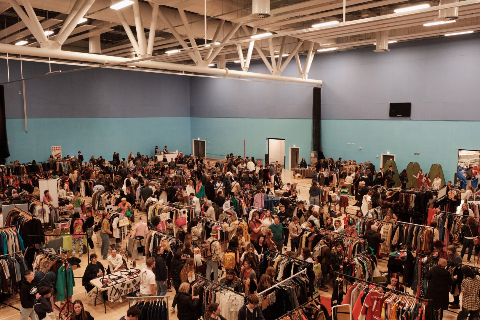 Crowds of people in large hall browsing stalls.