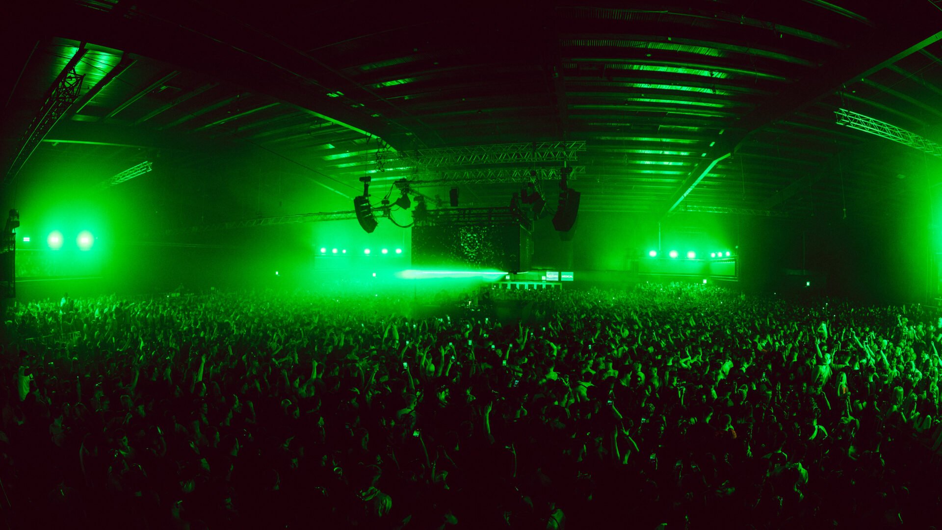 Crowd of people dancing under electronic lights.