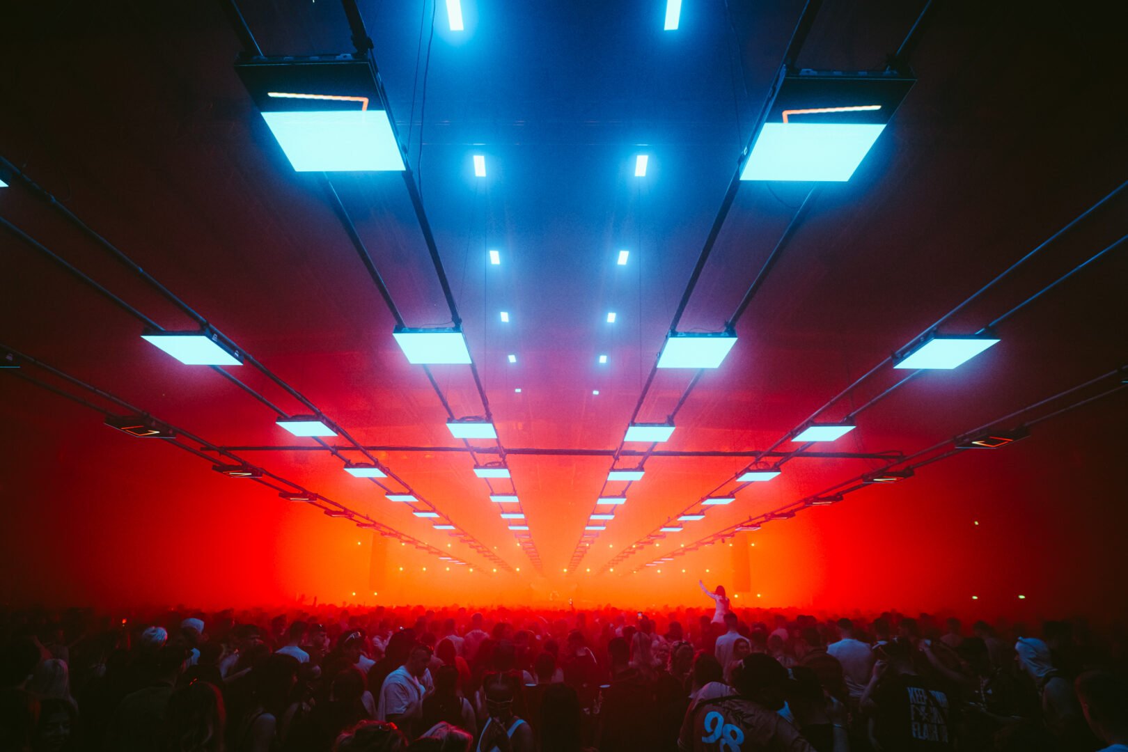 Crowd of people dancing under electronic lights.