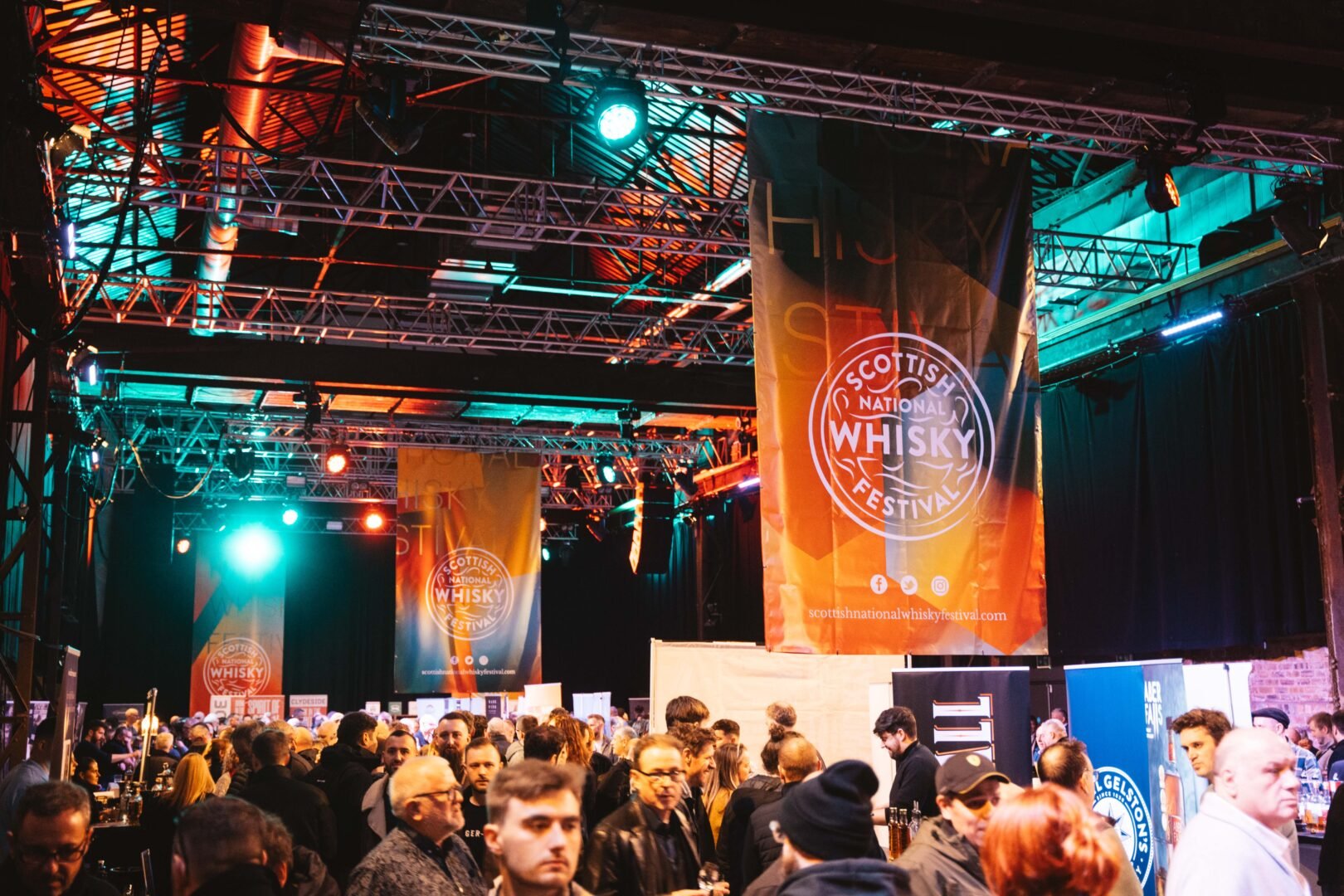 Crowds of people in large hall with banners overhead.