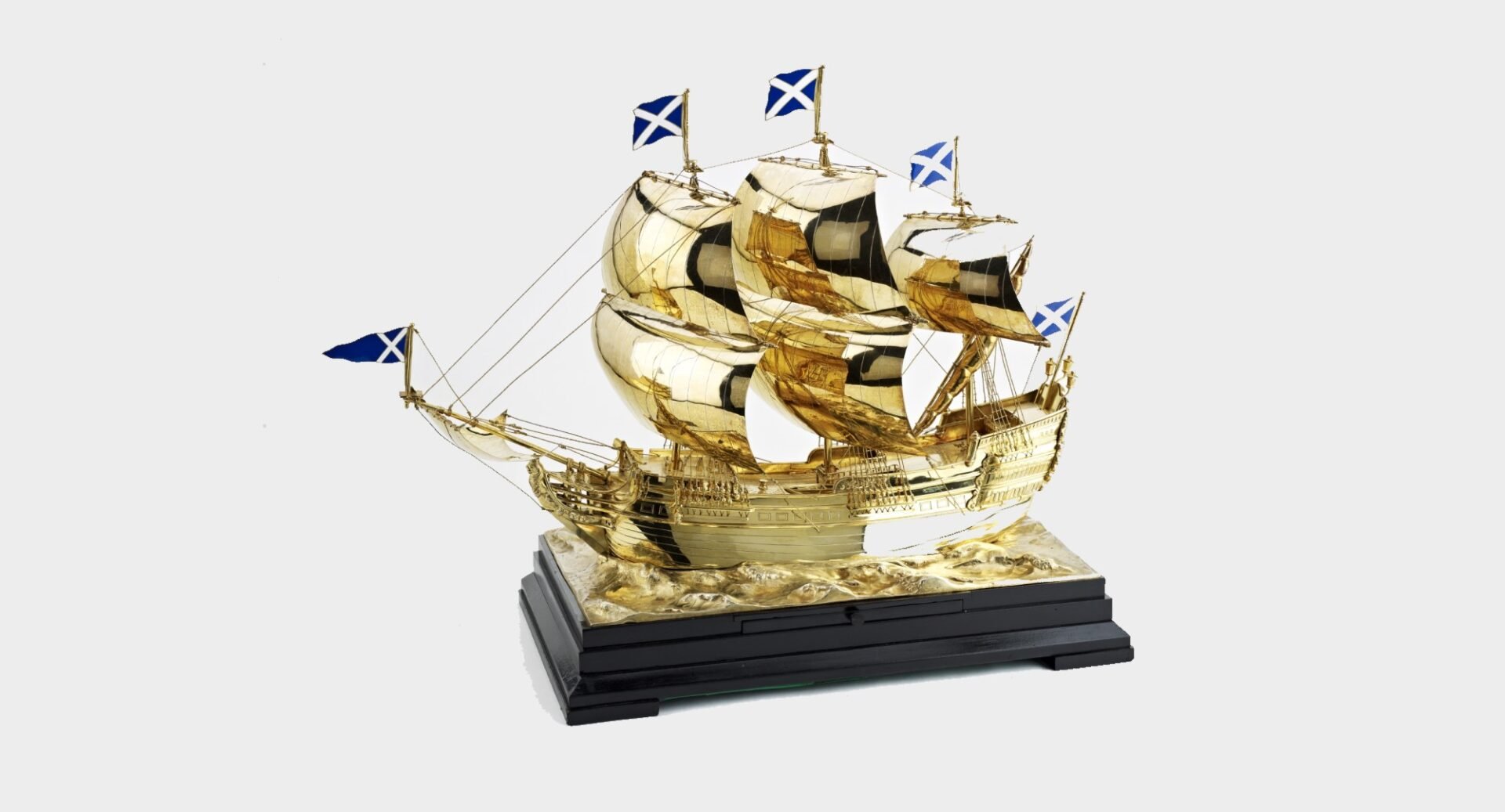 A gold galleon on a dark wood plinth, with saltires flying from the three masts, and fore and aft