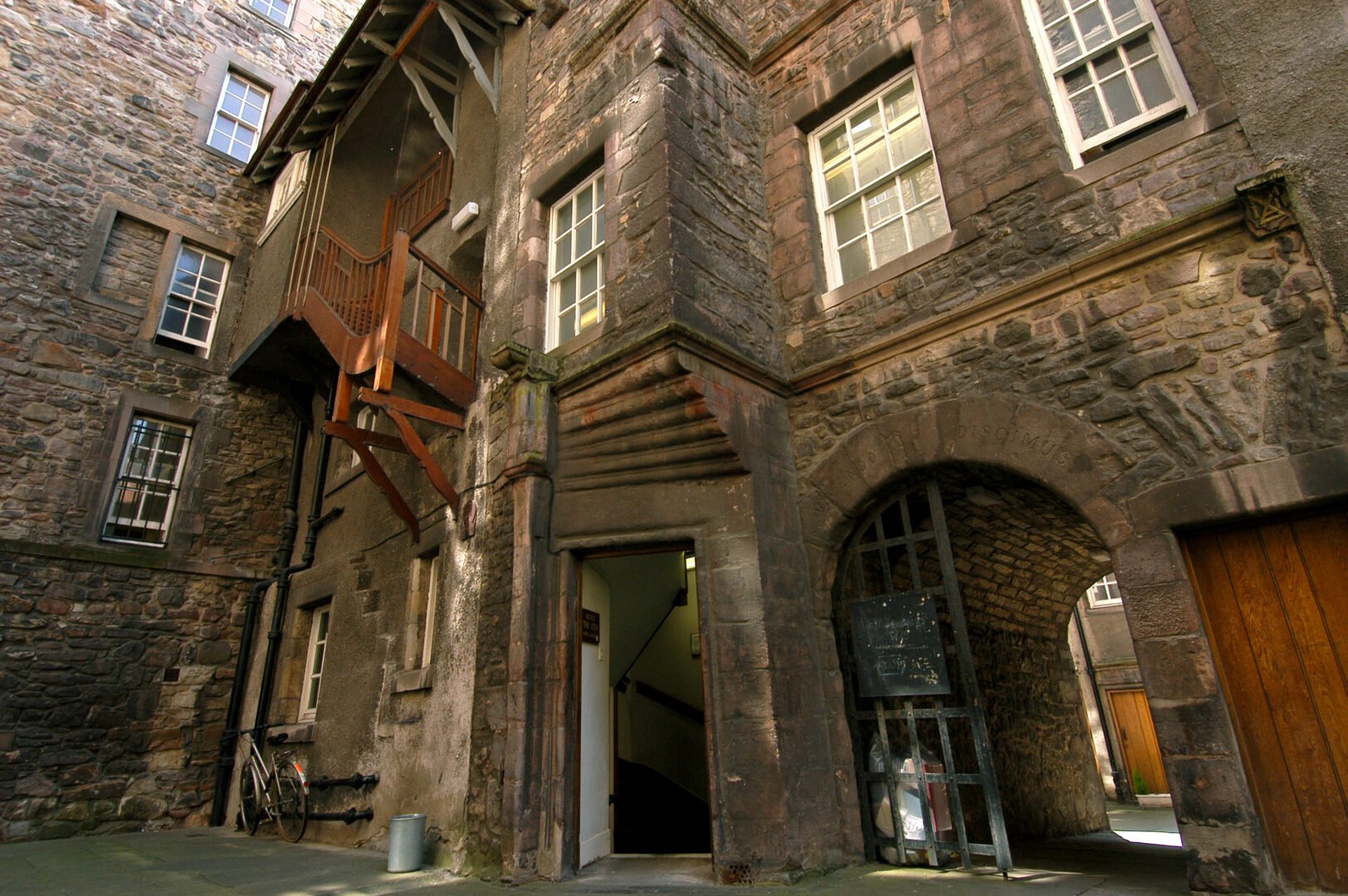 Riddles Court - a shot upwards almost from ground level of an old stone building with muntin windows, wooden balconies and an archway through to a rear courtyard