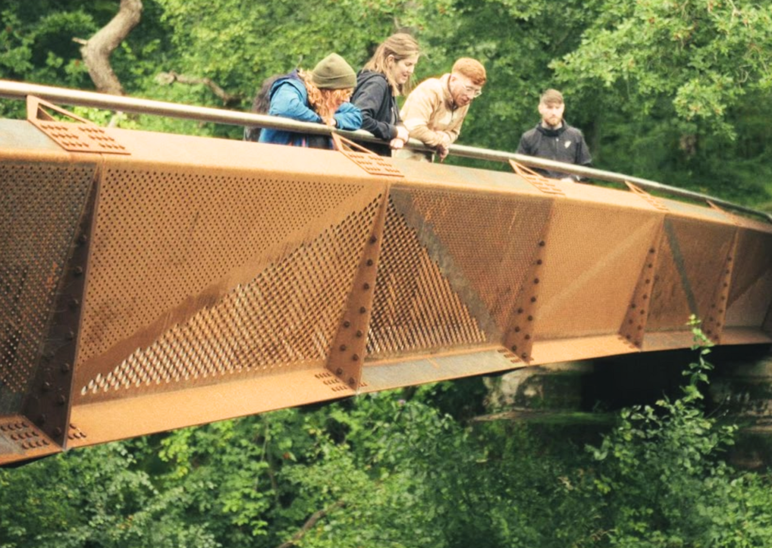 4 people looking over a bridge