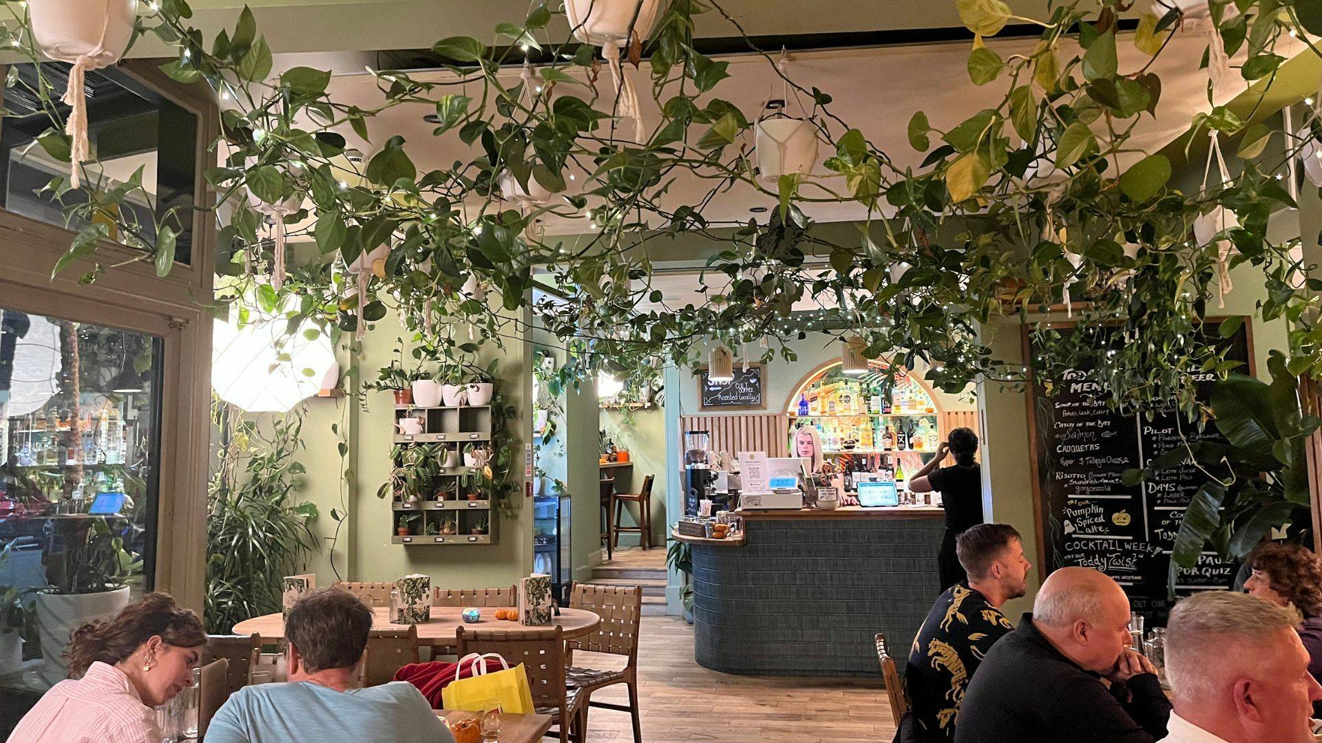 Plant filled restaurant with customers dining.