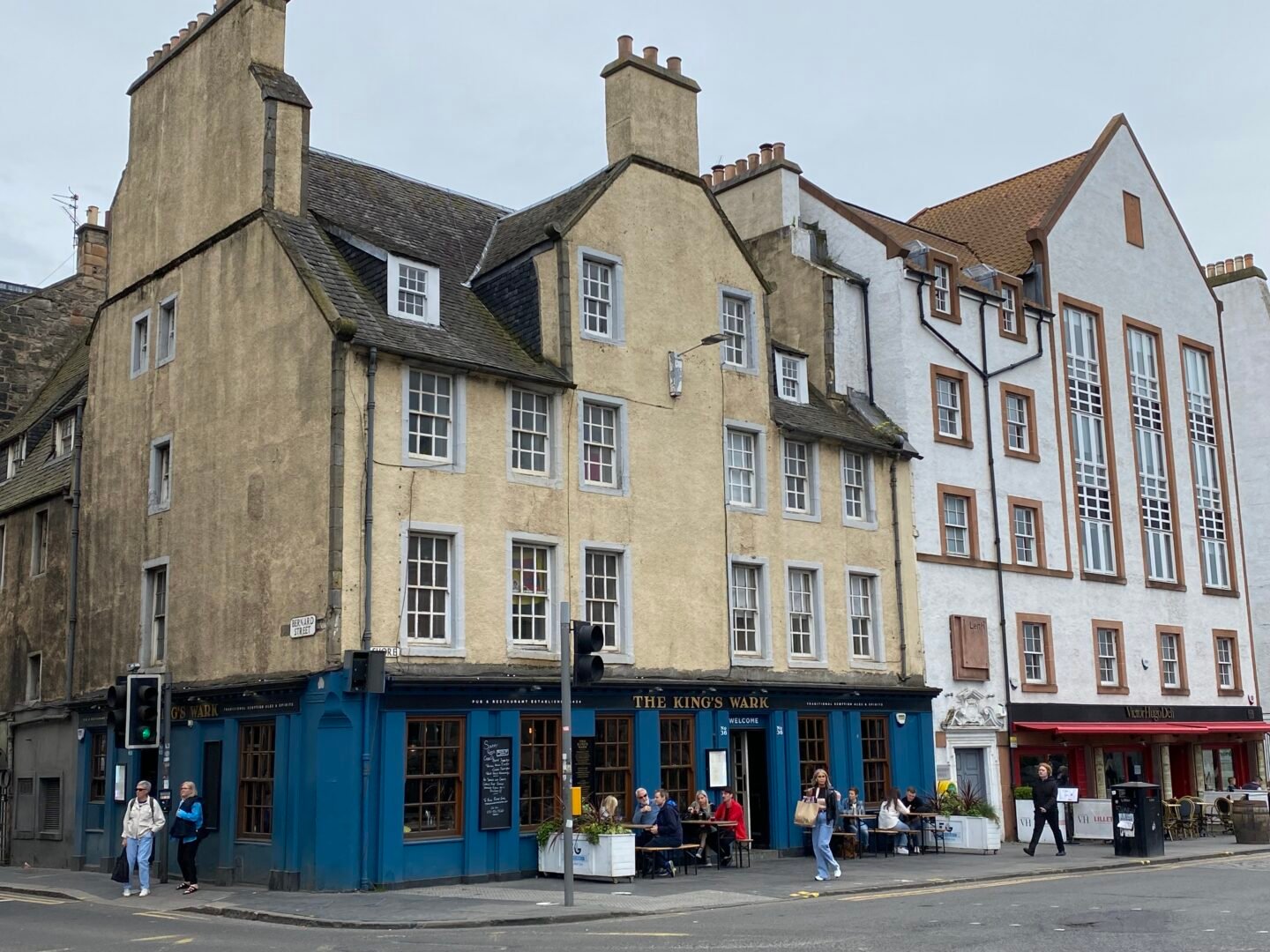 Exterior of 3-storey building, with steep gable sides, painted in yellow and blue.