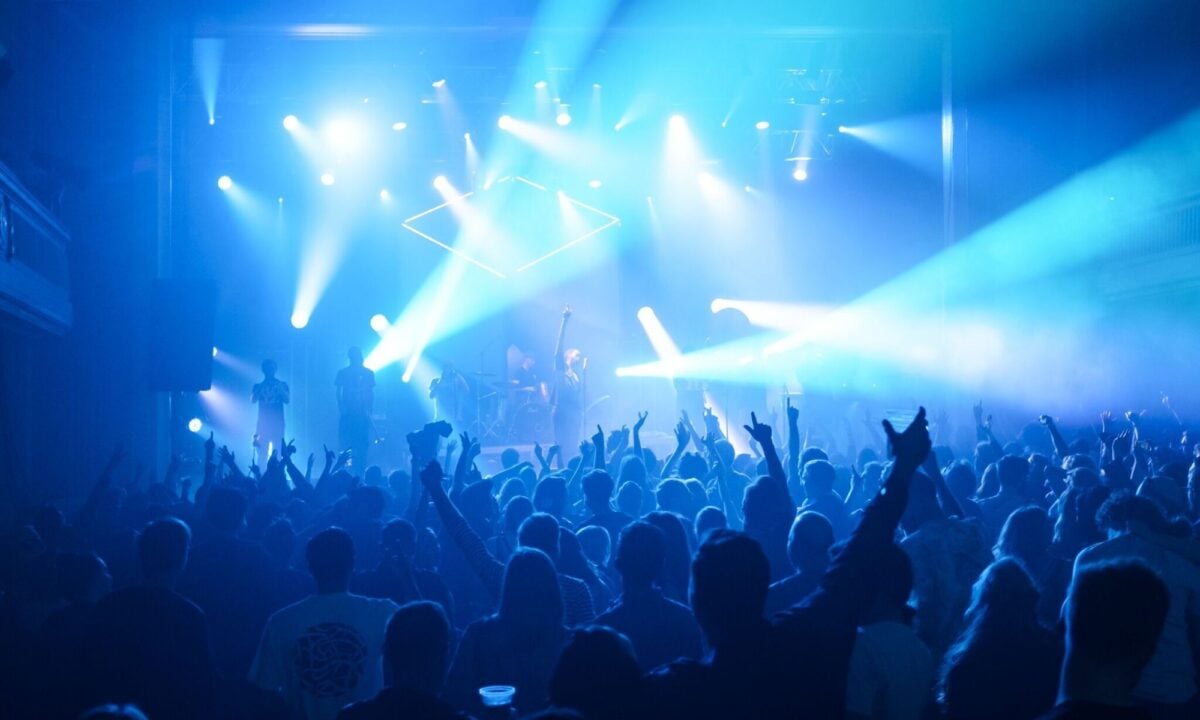 Group of people dancing in front of band performing on stage.