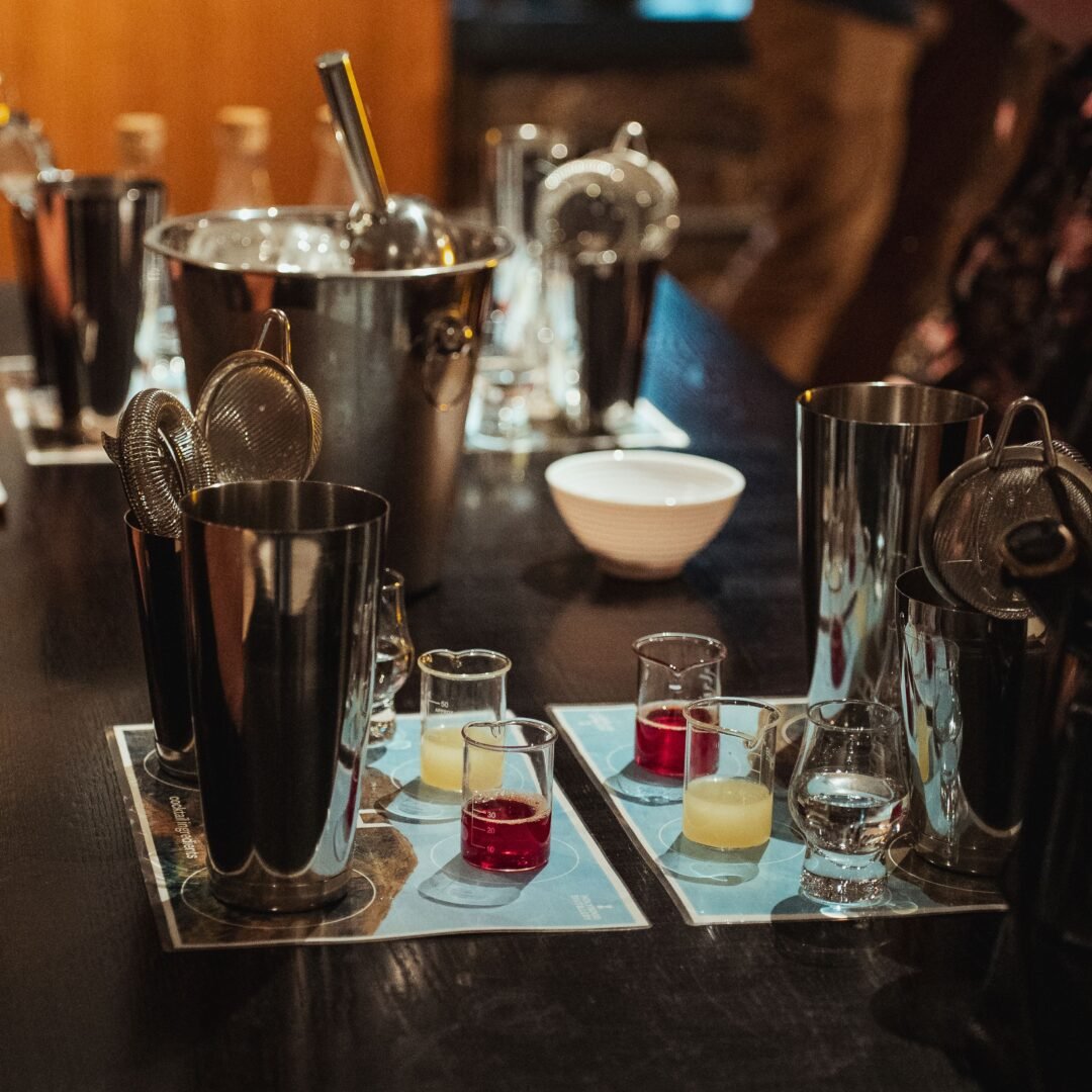 Table led with cocktail making utensils, including mixer, tub of ice cubes and glasses