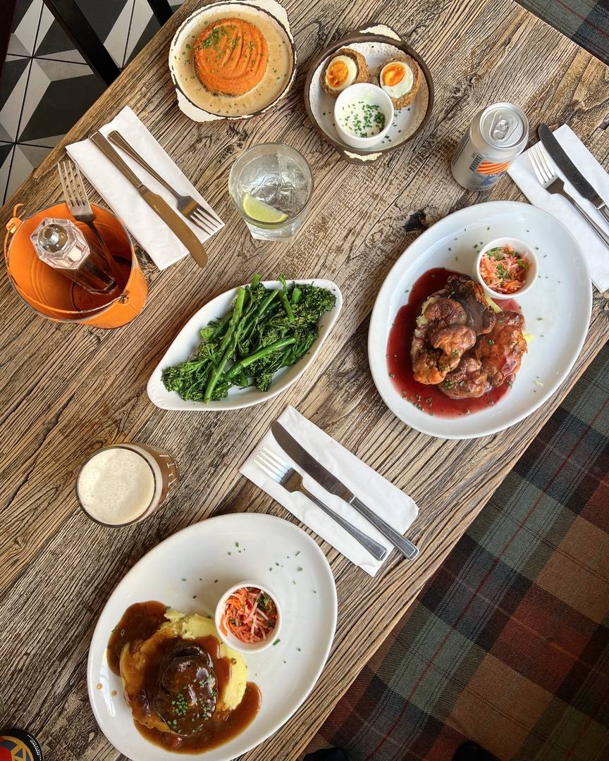 a table with a plate of haggis, a scotch egg, a lion's mane mushroom dish and a side of tender stem broccoli,© Makars Mash Bar