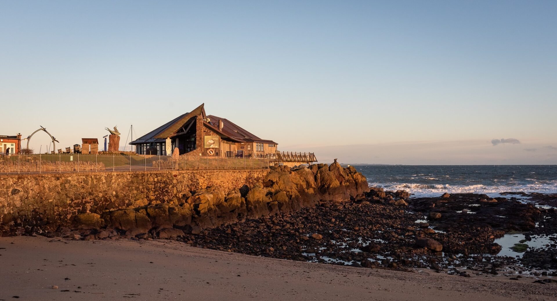 Dusky image of building built into cliff, looking out onto the water.