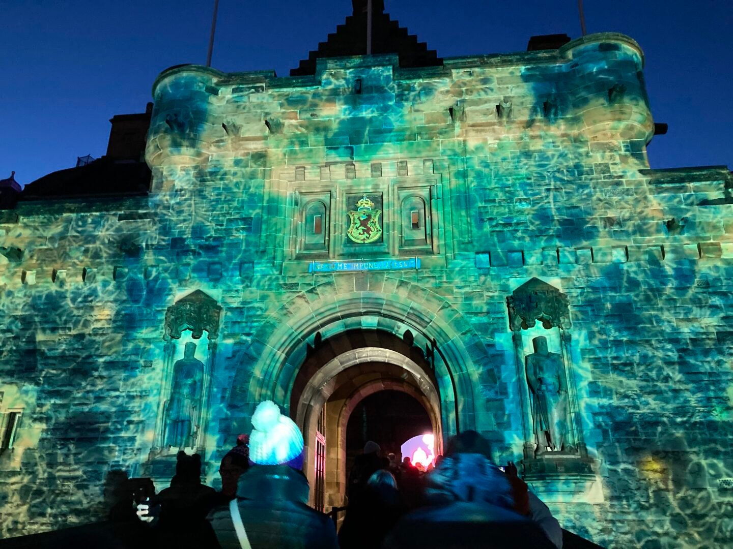 Exterior of castle building list up with green and blue lights.