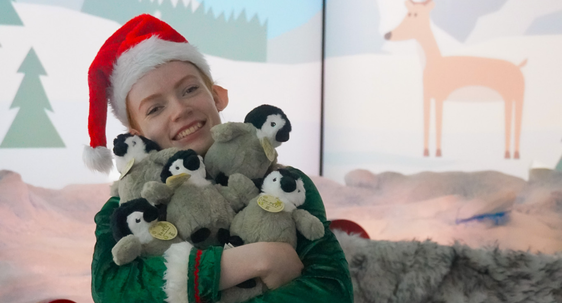 Child with red Santa hat cuddling 5 small toy penguins