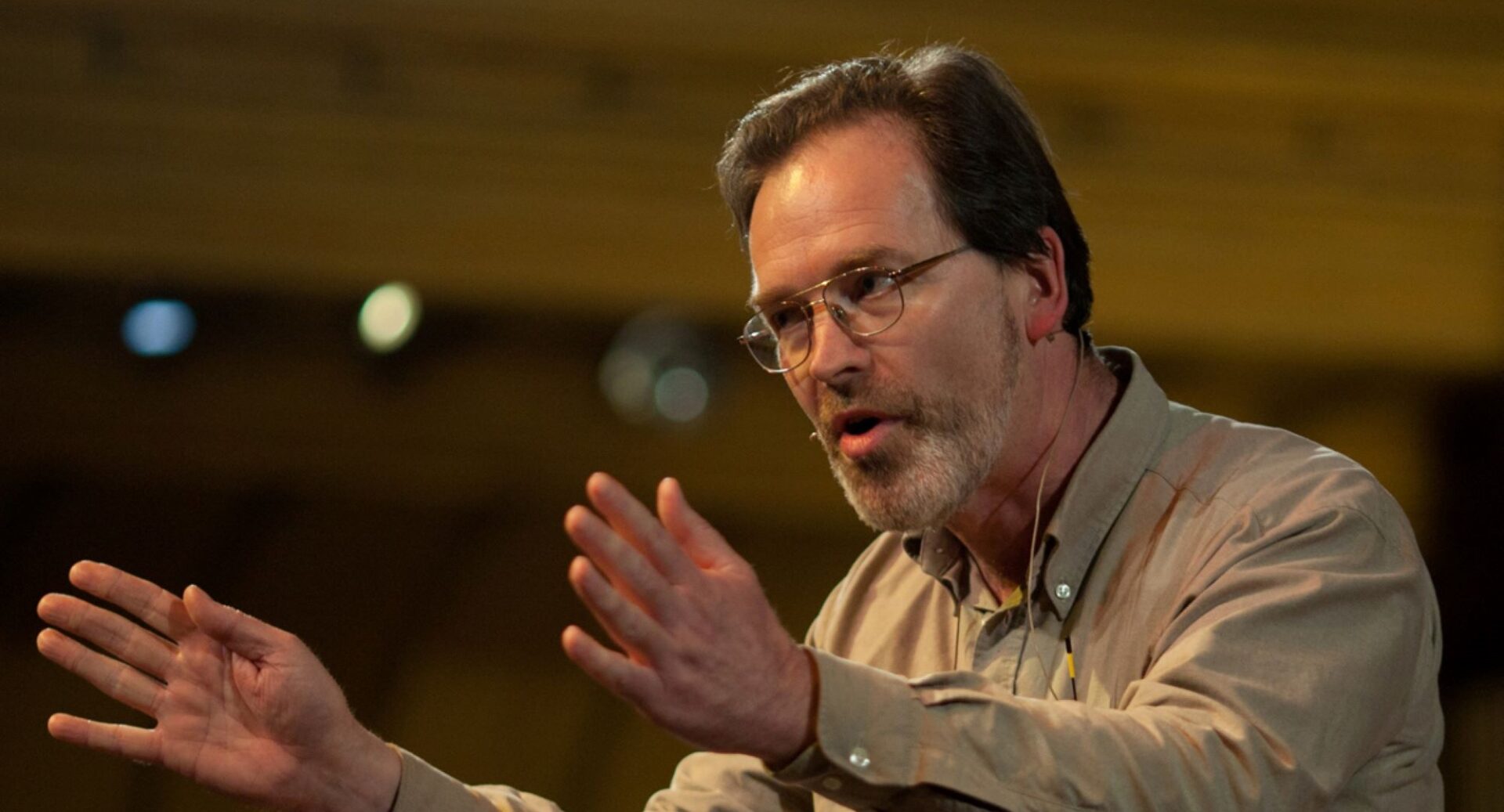 Donald Smith in a beige shirt, with hands outstretched, talking