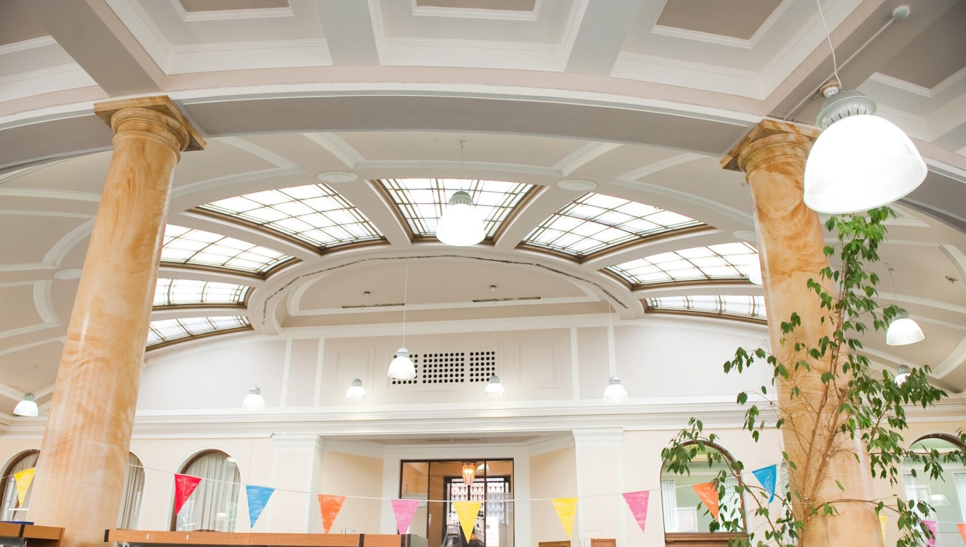 A shot of the interior of Leith Library, showing the white ceiling with skylights and a row of paper flags between marble effect pillars