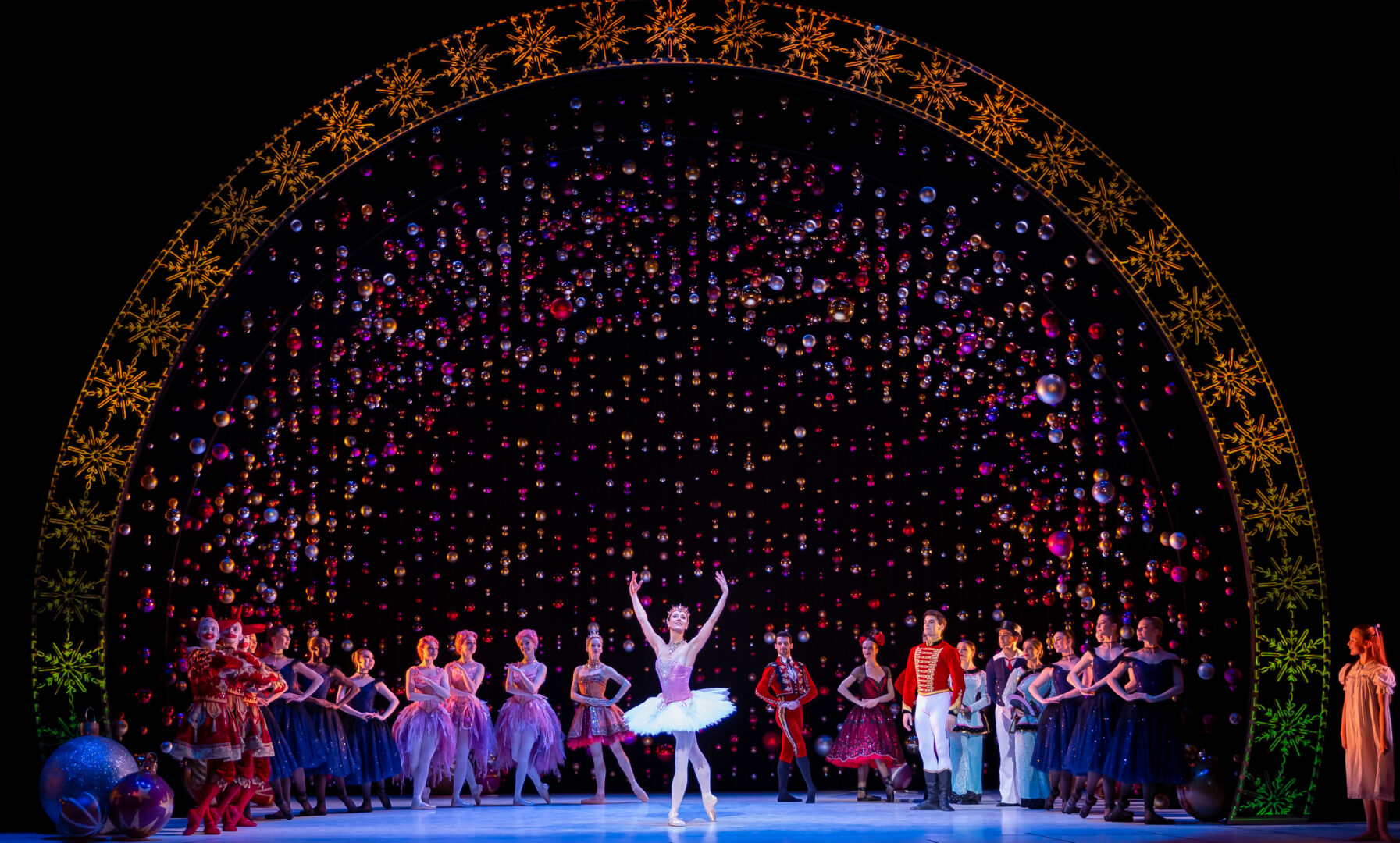 Group of people standing on a stage, with ballerina in the centre.