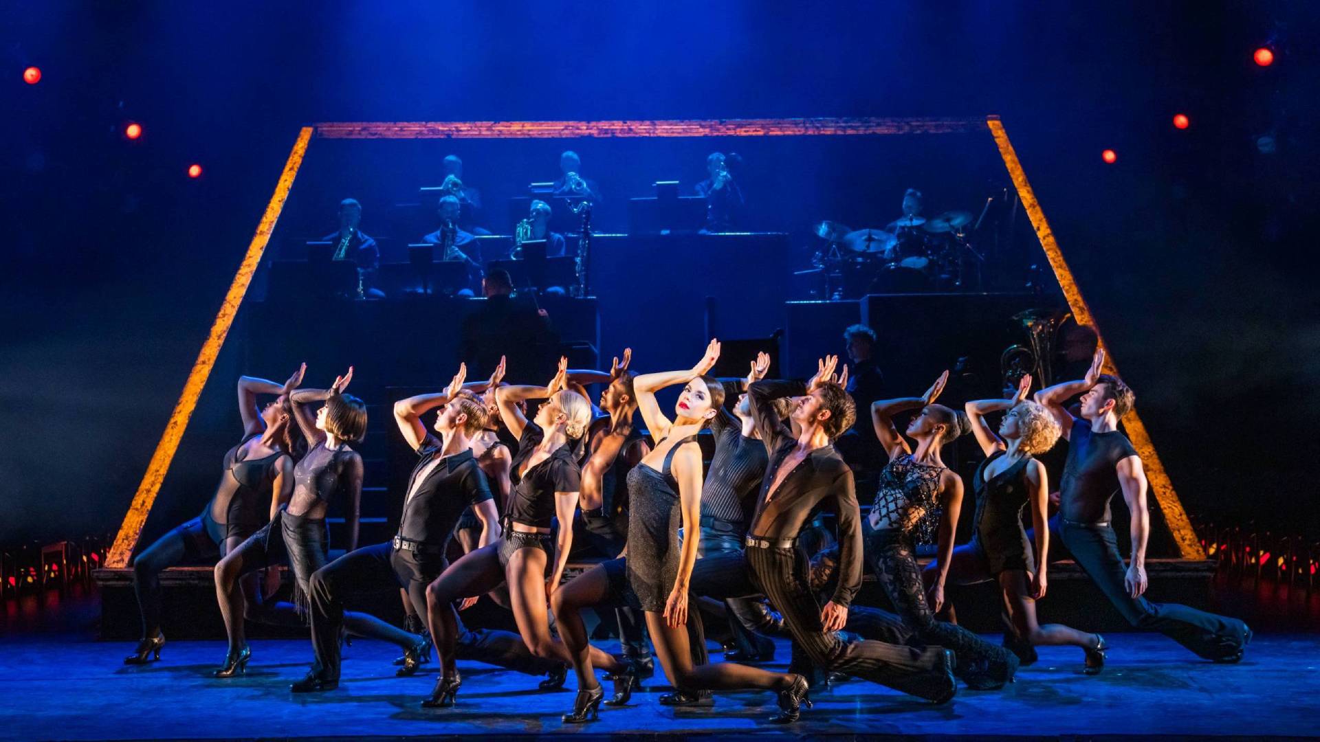 Group of dancers, all dressed in black, on stage.