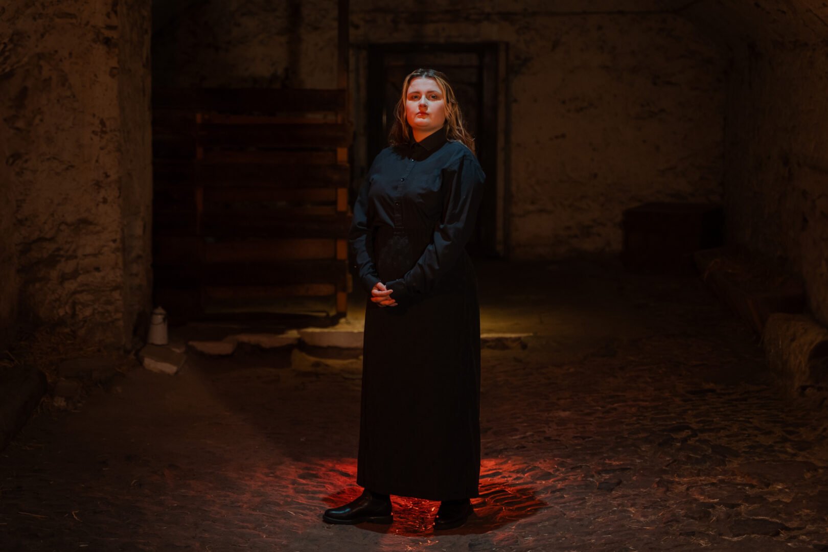 Women dressed all in black, standing in a dimly lit room.