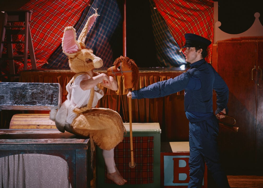 Person dressed in a brown rabbit costume and a man dressed all in blue facing each other.