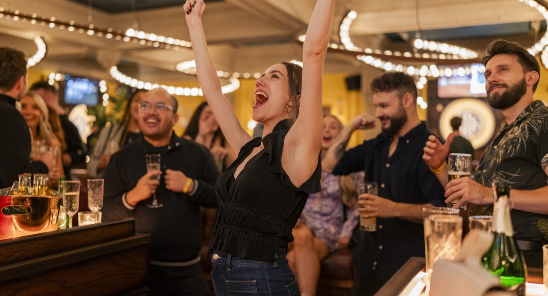 Women cheering, with arms in air, in bar.