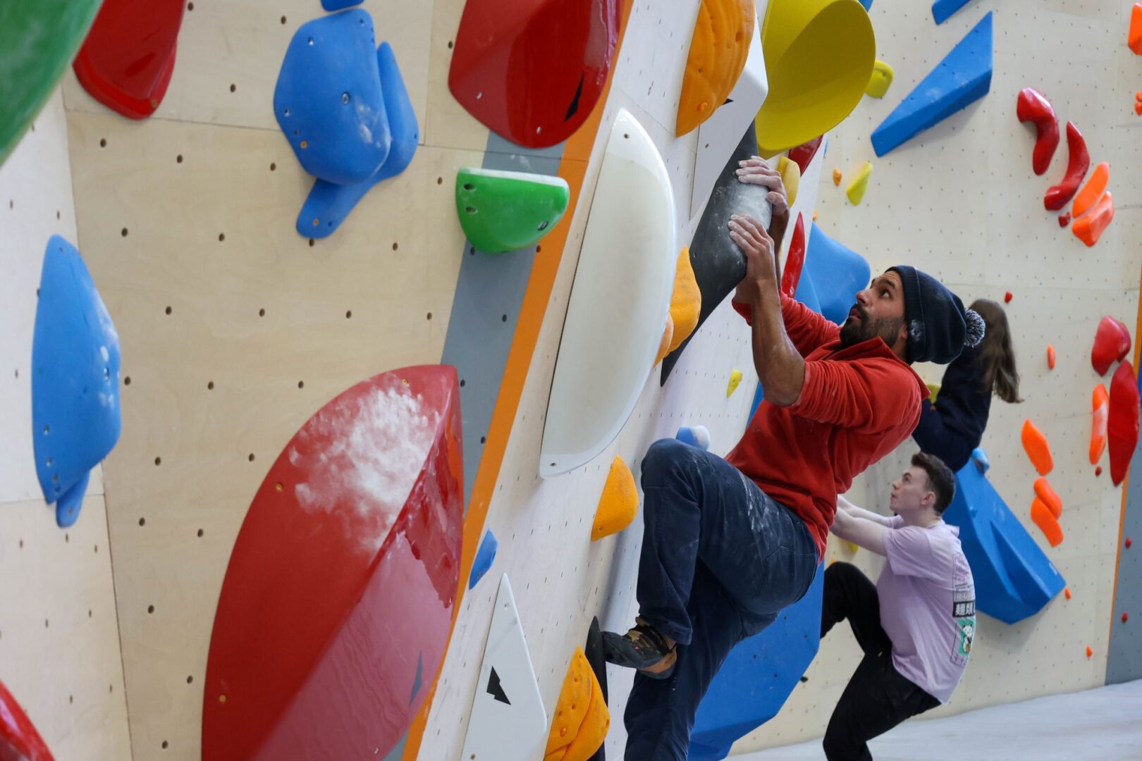 2 people climbing an interior bouldering wall.