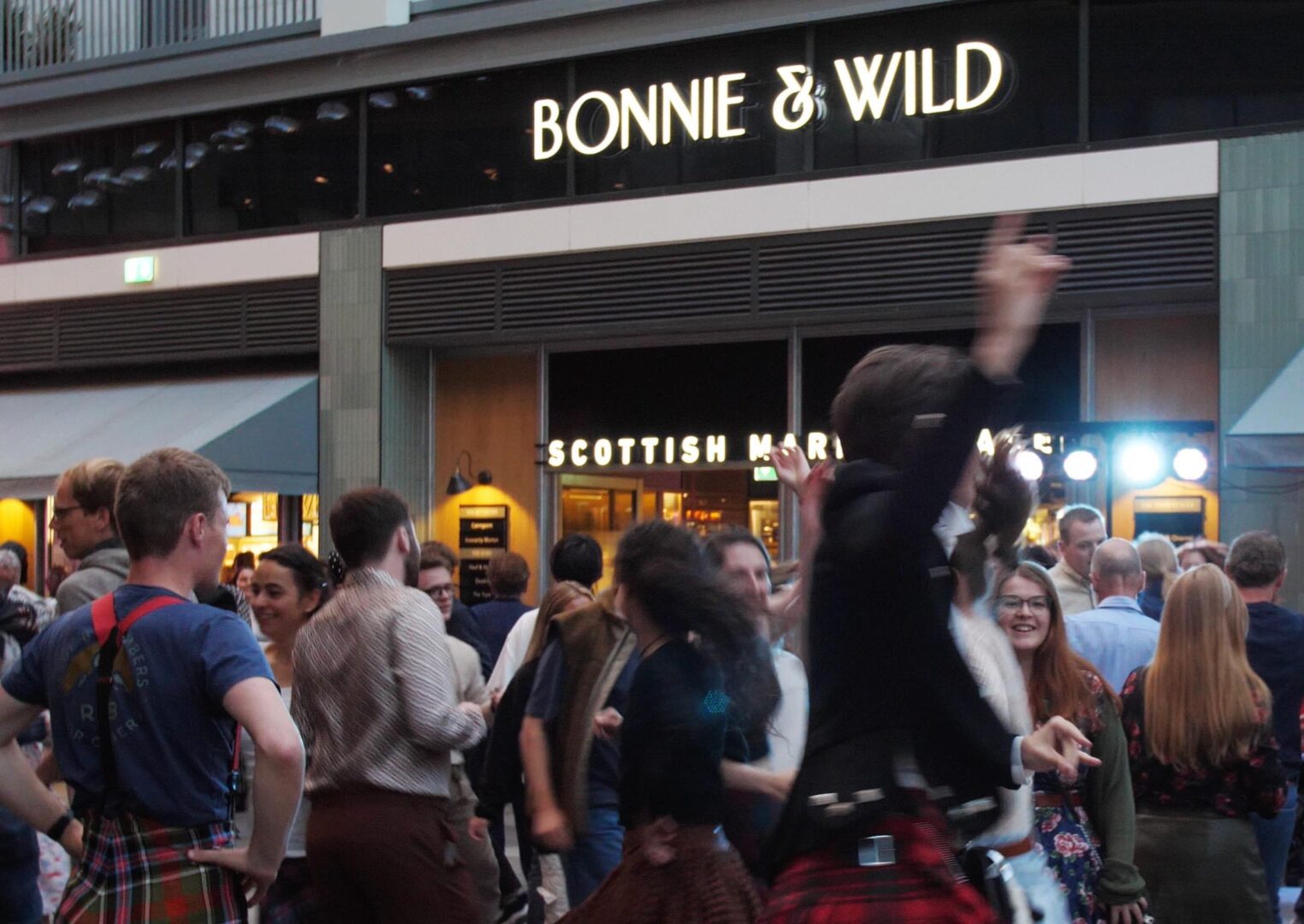 Group of people dancing , some of whom are wearing kilts.