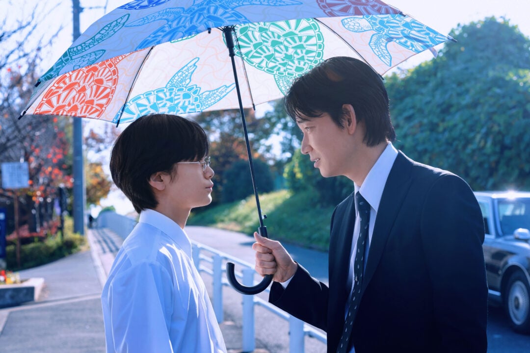 2 people in street standing under an umbrella.