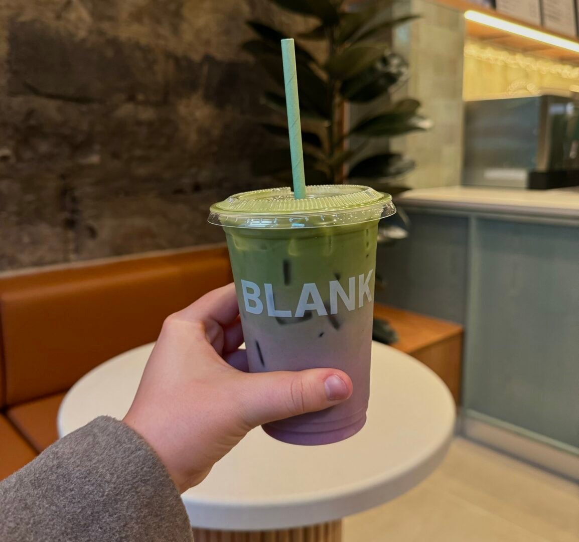 Person holding a purple and green drink in cup