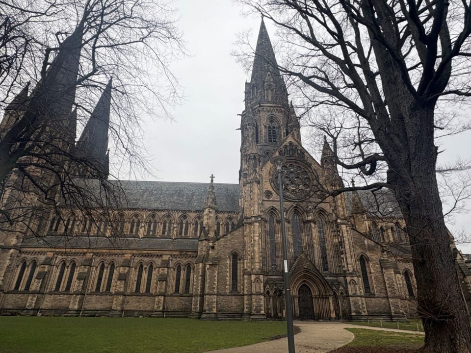 Cathedral with 3 spires, with bare tree in the foreground.