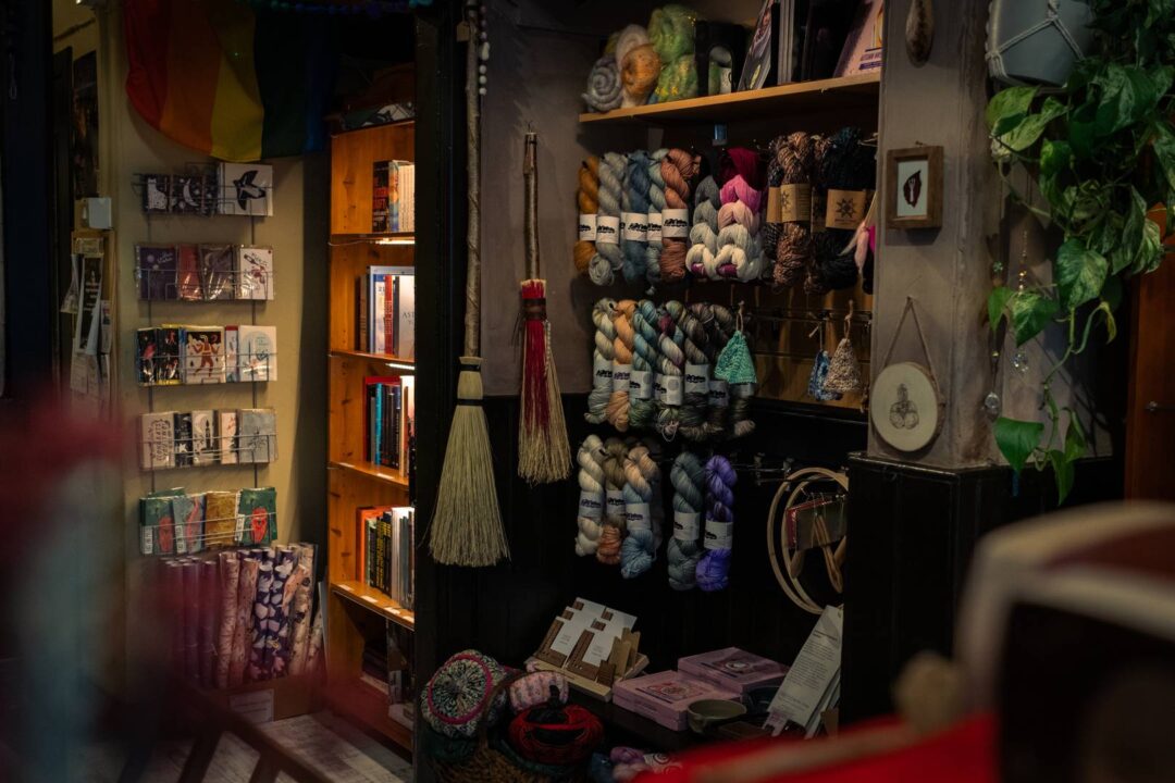a display of colourful skeins of yarn and wool, with cobweb brooms and greeting cards